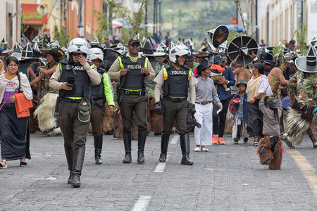 June 29, 2017 Cotacachi, Ecuador: police supervising kichwa indigenous people dancing on the street during Inti Raymi festivalのeditorial素材