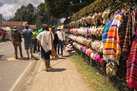 August 6, 2017 Medellin, Colombia: tourists walk by hats and ponchos hung on the fence by vendors  during the flower festival in the Piedra Gorda areaのeditorial素材