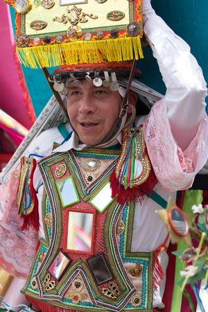 June 17, 2017 Pujili, Ecuador: large heavy religious headdress balanced on male dancers head during Corpus Christi paradeのeditorial素材