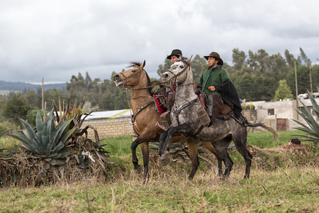 June 10, 2017 Toacazo, Ecuador: cowboys wearing traditional poncho riding their horses in the rainのeditorial素材