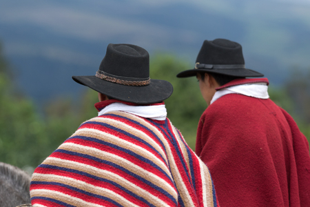 Machachi, Ecuador: closeup of indigenous quechua cowboys on horseback  dressed traditionally in colorful ponchoの写真素材