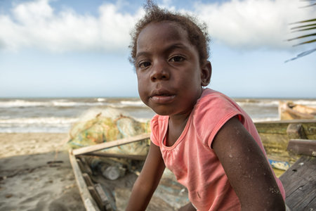 March 11, 2015 Sambo Creek, Honduras: a young garifuna girl part of the fishing community on the carribbean coast of the country sits on a dugout canoeのeditorial素材
