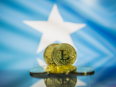 Bitcoin gold coin and defocused flag of Somalia background. Virtual cryptocurrency concept.の写真素材