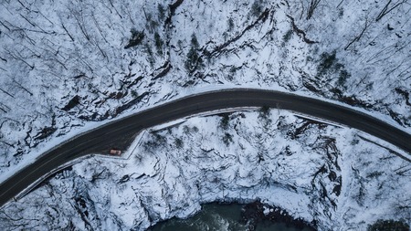 Tourist cars driving down asphalt road running along the emerald riverの写真素材