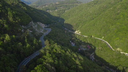 Aerial view over mountain road going through forest landscape, Winding road from high mountain pass.の写真素材