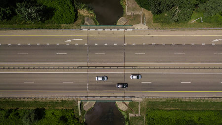 Top down close up of highway traffic, white arrow signs indicating direction