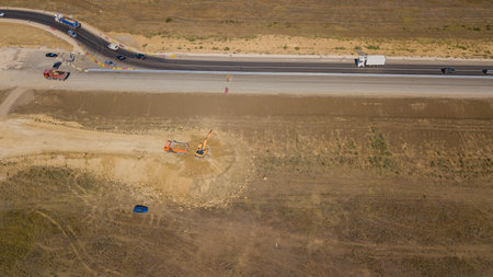 Aerial road constructions, machinery and mine equipment near road on sandy surface