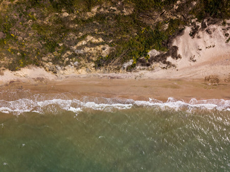 Top down view of waves breaking in the sand, flying over tropical sandy beach and waves