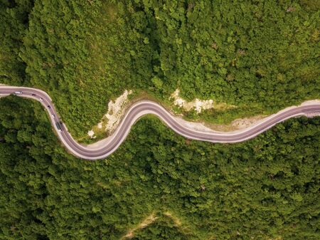Mountain winding zig zag road. Top aerial view: cars driving on road from above.の写真素材