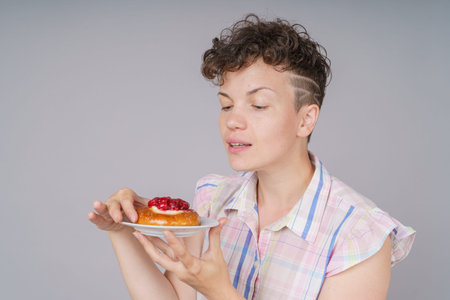 Funny girl with cake on gray background