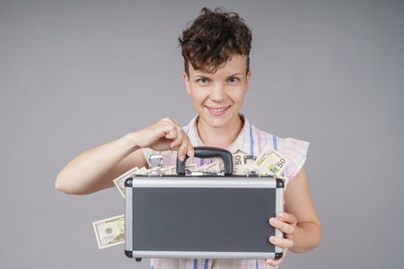 Pretty Woman is holding a suitcase with copyspace in studio. Isolated gray background.の写真素材