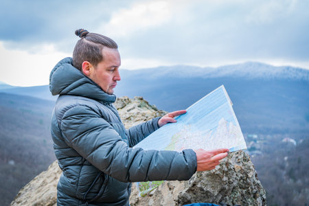 Well-dressed man working with laptop sitting on the rocky mountain on beautiful scenic clif backgroundの写真素材