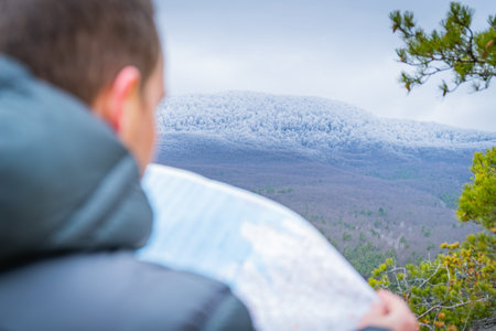 Traveler checks map to find directions in wilderness area, selective focus - main subject:...