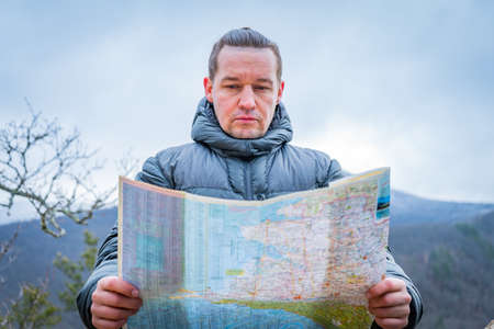 Well-dressed man working with laptop sitting on the rocky mountain on beautiful scenic clif backgroundの写真素材