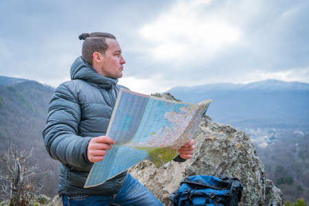 Traveler checks map to find directions in wilderness area, selective focus - main subject: snow-capped mountainsの写真素材