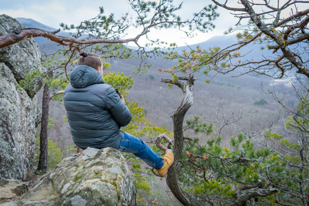 Traveler with monocle sitting on a mountain cliff and looks into the distance.の写真素材