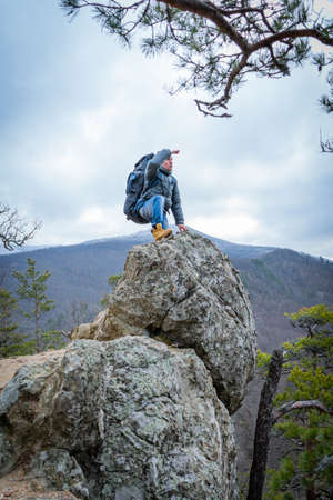 The traveler climbs to the top of the cliff and look into the distance, hiking, travel concept.の写真素材