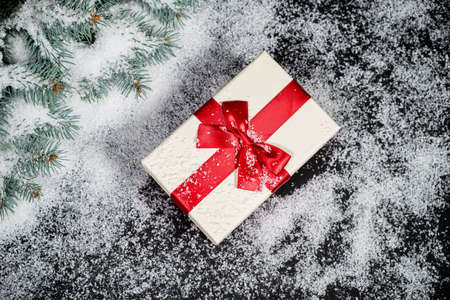 Decorative red Christmas gift in winter snow with a blank label for your seasonal greeting.の写真素材