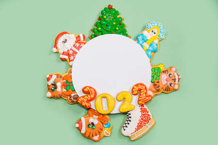 Christmas composition with gingerbread colorful cookies on the green background. Flat lay. Merry Christmas, New Year, winter concept.の写真素材
