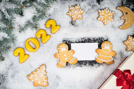 Christmas background with gingerbread on winter snow. Holiday mood card. Top view, copy space....