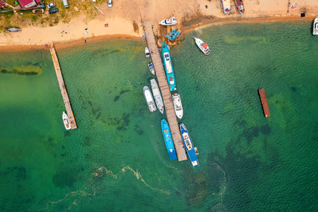 Boats and yachts on the pier at an uninhabited sandy island on Lake Baikal, Siberia.