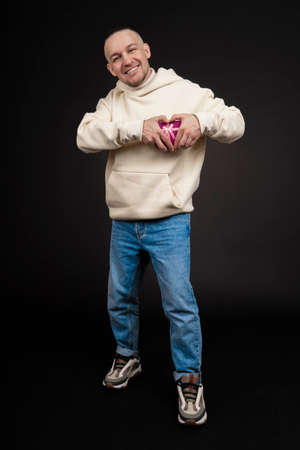 Happy handsome man giving a gift, on black backgroundの写真素材