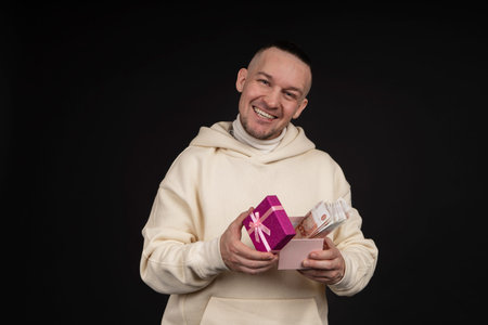 Happy handsome man giving a gift with money ruble, on black background