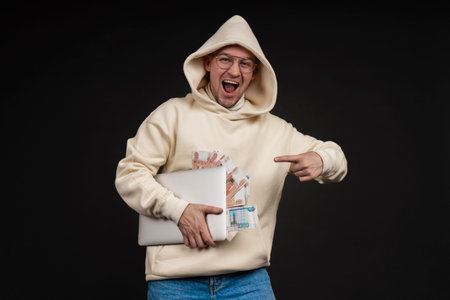 Young happy businessman with a notebook and stack of money isolated on black background. Selective...
