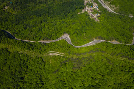 Aerial view of winding road from the high mountain pass. Great road trip trough the dense woods. Birds eye view.の写真素材