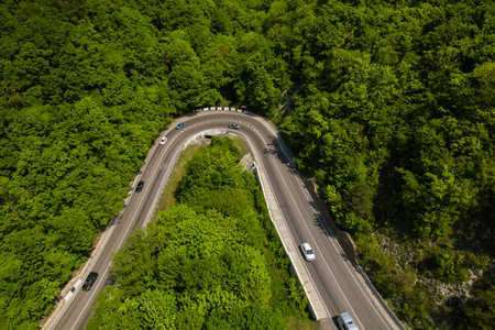 Aerial view of winding road from the high mountain pass. Great road trip trough the dense woods....