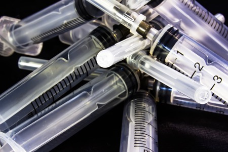 Plastic medical syringe, on black background.の写真素材