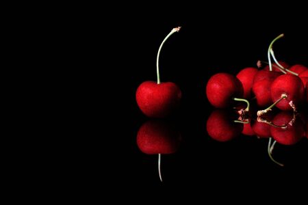 bunch of red cherries on a reflective black backgroundの写真素材