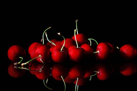bunch of red cherries on a reflective black backgroundの写真素材