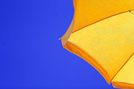 yellow parasol against summer blue skyの写真素材