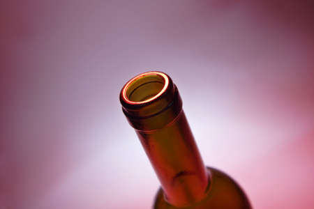 opened bottle of red wine on red ambient backgroundの写真素材