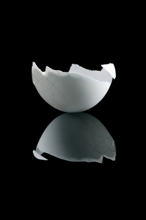 cracked white hens egg on reflective black surface.contradictory opposite reflectionの写真素材