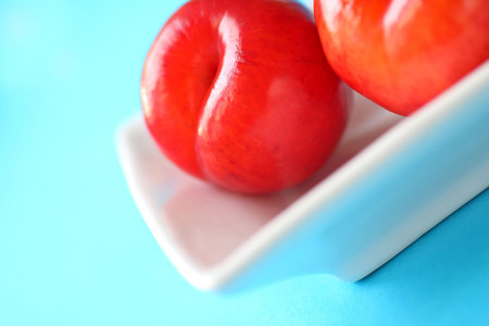 fresh red ripe plums, served in a white dish. shallow depth of field.の写真素材