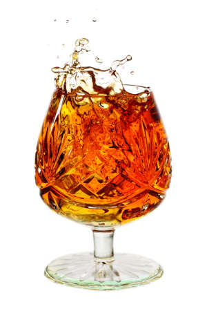 snifter glass full to the brim with brandy and splashの写真素材