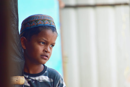 Hyderabad, India - March 05, 2020:  A young Rohingya 7 year old child stands alone at the side of the Rohingya refugee camp at Balapur, Hafiz Baba Nagar camp in Hyderabad, India - March 05, 2020.のeditorial素材