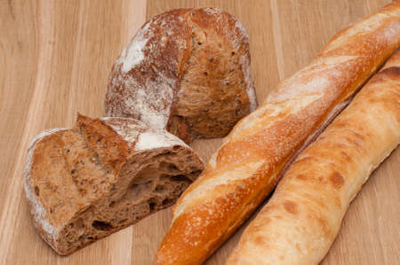 Sliced bread and two baguettes on a wooden board backgroundの写真素材