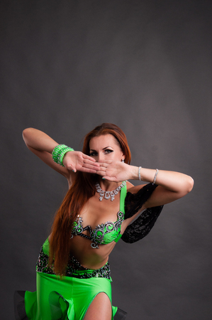 Beautiful slender woman dancing belly dance sexy Arabian Turkish oriental professional dancer in a bright, carnival shining suit with long hair.の写真素材