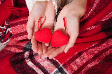 Valentine's Day, two red hearts in female hands. Concept of love, feelings, relationships. Hands close upの写真素材