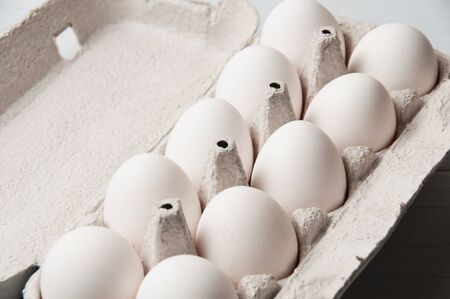 White chicken eggs in tray on a light wooden background, copy spaceの写真素材