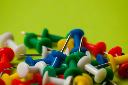 Many thumbtacks of different colors on green designer paper.