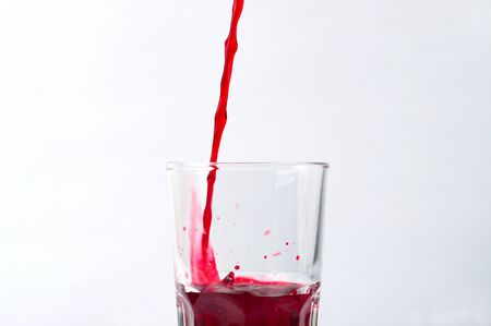 Grape and pomegranate juice pouring into a glass, isolate on a white backgroundの写真素材