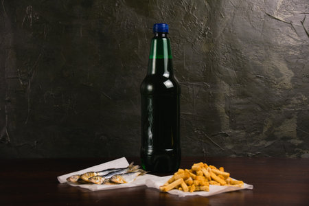 Dried fish, salty white bread crackers and beer in a plastic bottle on a dark backgroundの写真素材