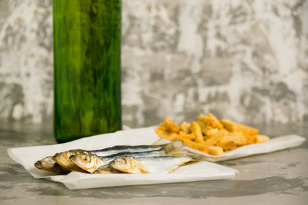 Delicious beer snack salted dried fish, salted wheat bread crackers and light beer in a glass bottle on a light background.の写真素材