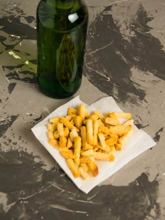 Flatlay, tasty beer snack salty wheat bread crackers and light beer in a glass bottle on a gray background.の写真素材