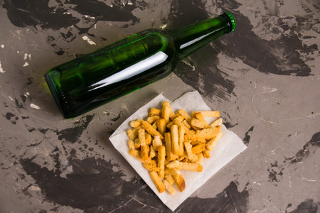 Flatlay, tasty beer snack salty wheat bread crackers and light beer in a glass bottle on a gray...