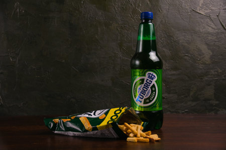 Ukraine, Chernihiv, June 24, 2023: Light beer in a plastic bottle and salty crackers with the taste of mushrooms on a dark background.のeditorial素材